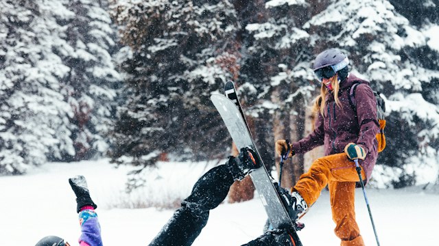 Two friends in ski gear in a snowy pine forest near Breckenridge