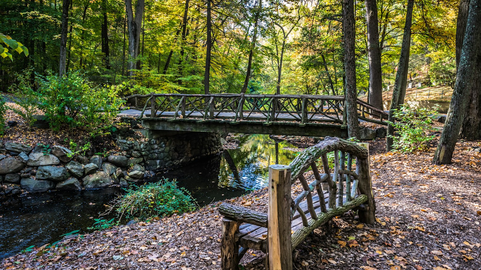 An autumn bench and footbridge in Sleepy Hollow Cemetery