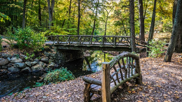 An autumn bench and footbridge in Sleepy Hollow Cemetery